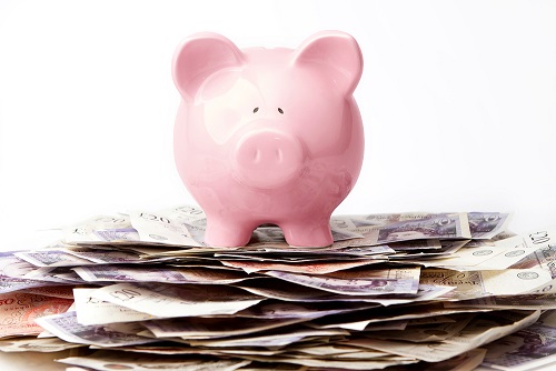 Piggy bank on a pile of British bank notes.